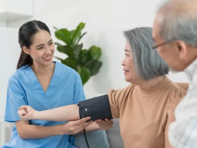 Elderly woman going for health screening with a nurse taking her blood pressure.